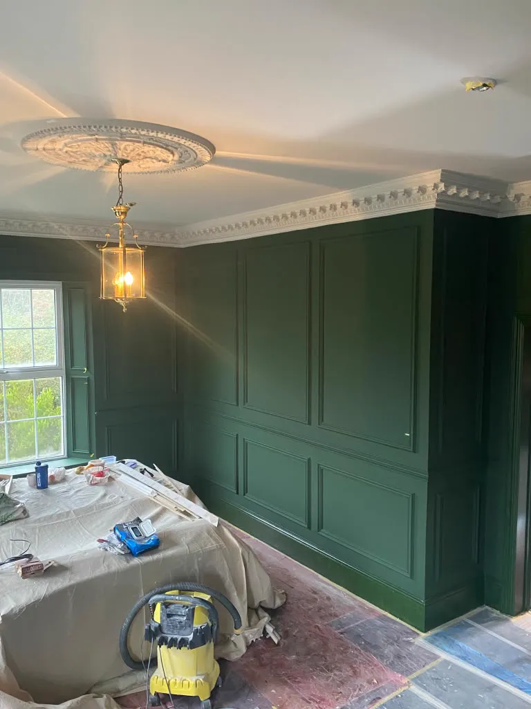 Dining room wall panelling painted deep green under white crown molding
