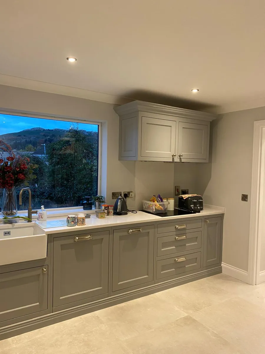 Kitchen cabinets painted soft grey, with a farmhouse sink and a big window
