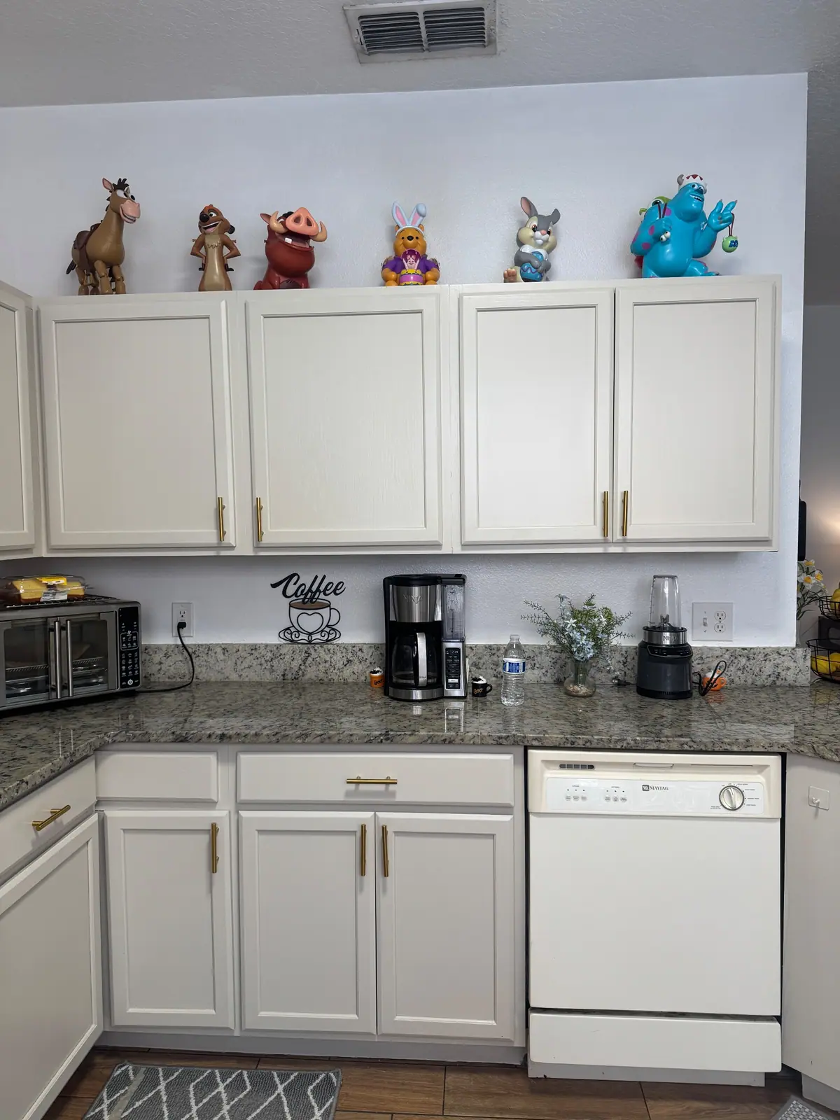 Cream upper cabinets with brass pulls above the dishwasher