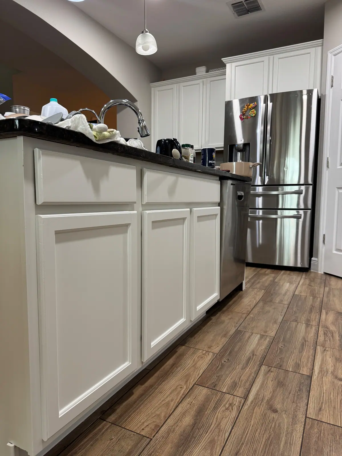 Island cabinets painted white beside a stainless fridge
