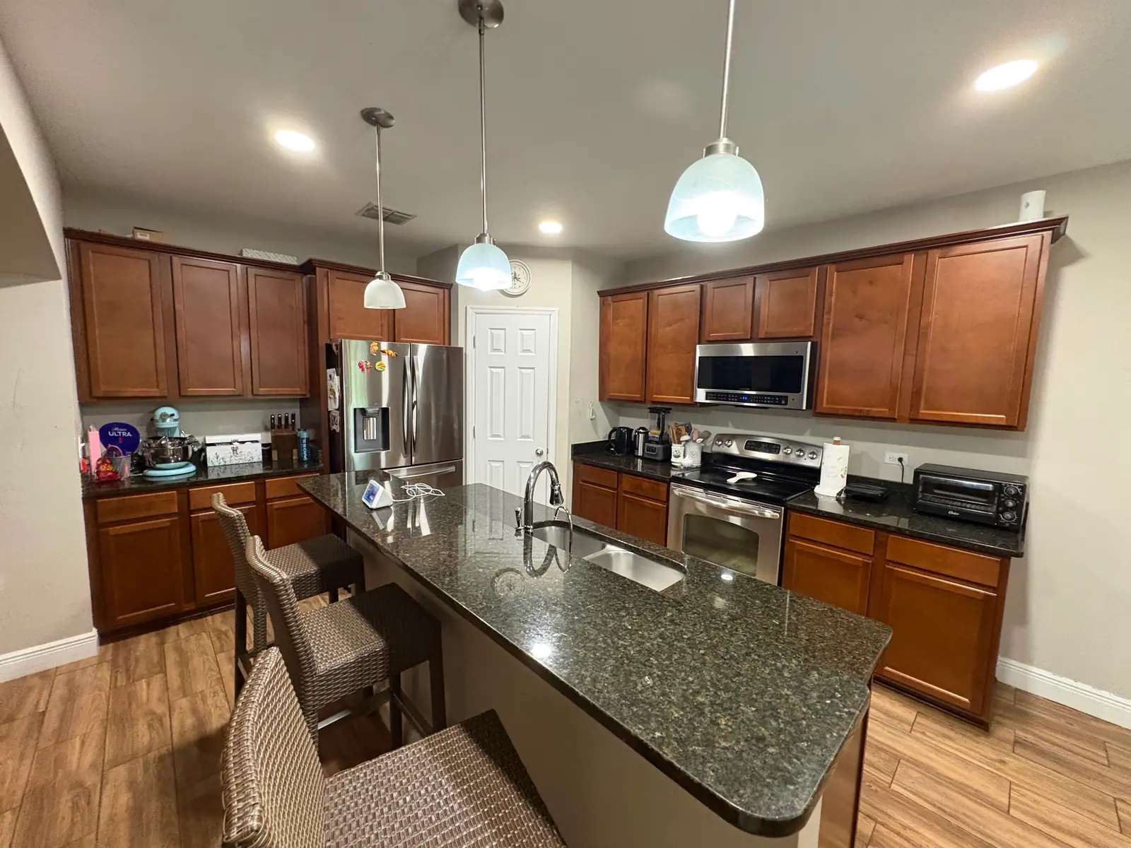 Kitchen with cherry stained cabinets and a granite island before painting