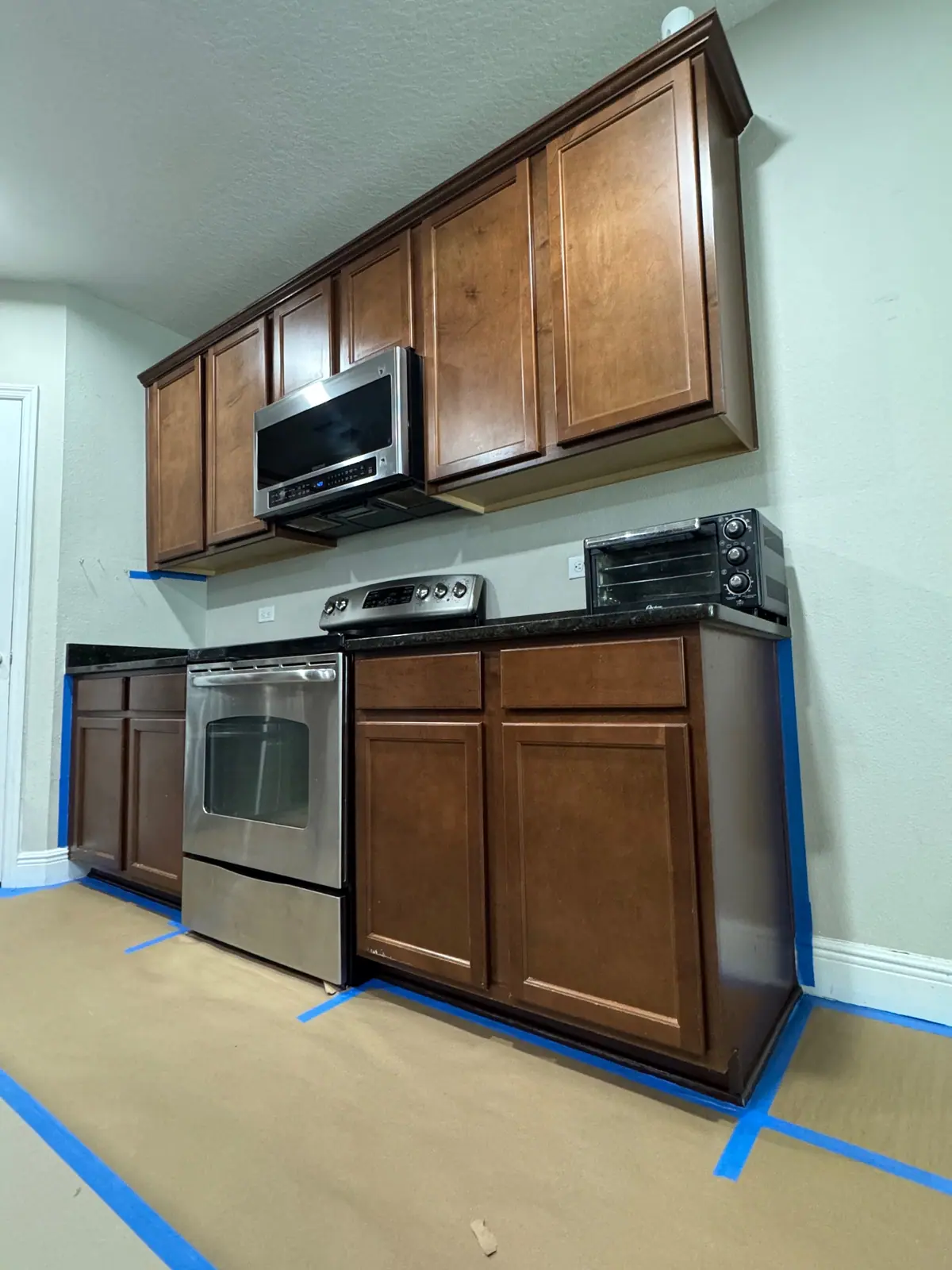 Range wall cabinets with floor paper and blue tape before painting