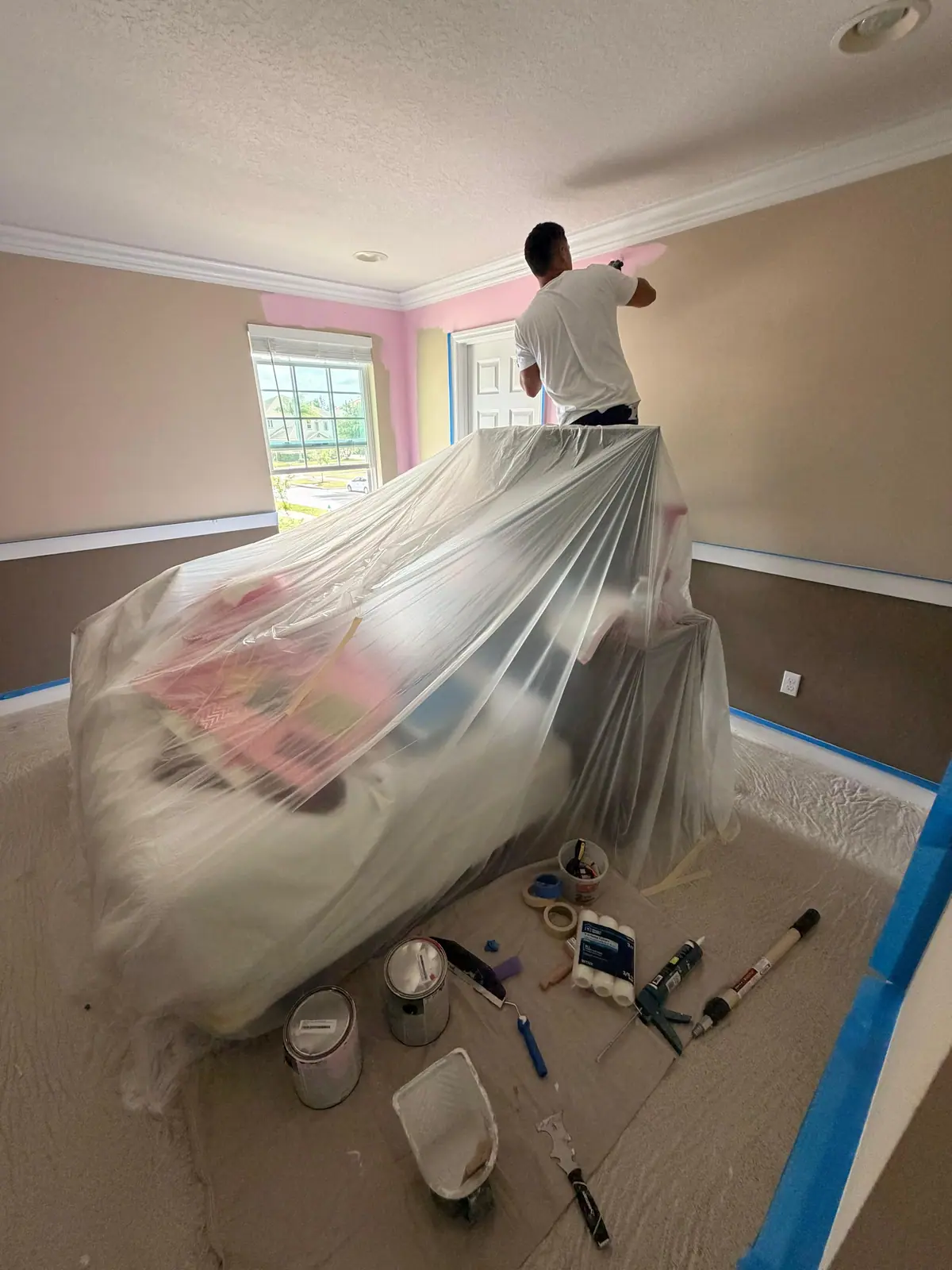Bedroom furniture sealed under plastic with the floor covered during painting